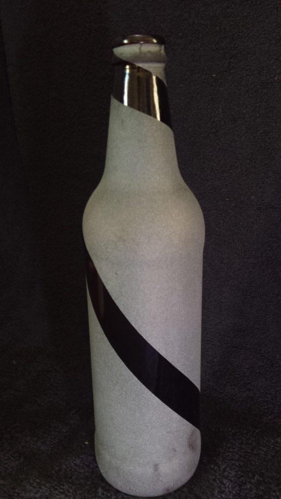 A brown glass bottle reverse etched with a single spiral stripe