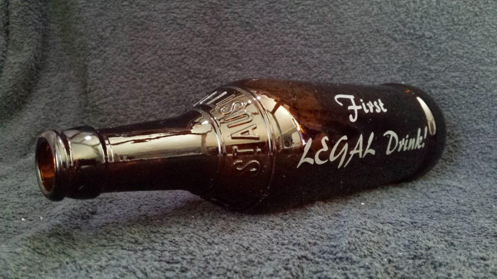 A beer bottle etched as a memory artifact from a coming of age celebration