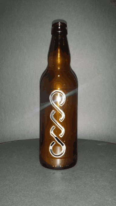 A brown craft beer bottle with a carved celtic knotwork design and cutout for a tealight